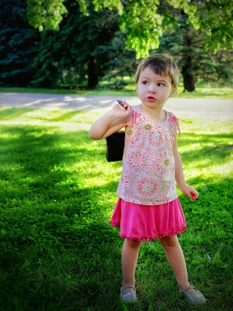 Photo full length of cute girl with toy standing on grassy field