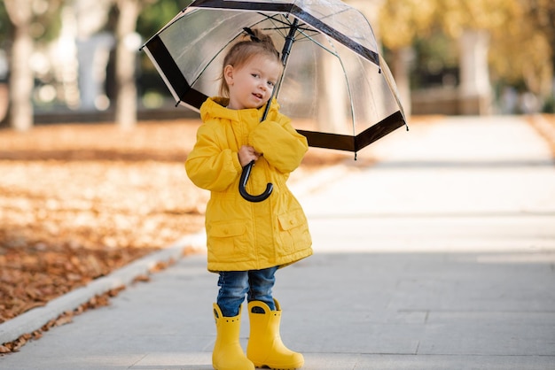 Full length of cute girl with umbrella standing on footpath