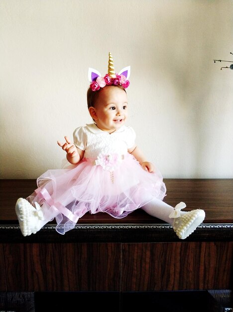 Photo full length of cute smiling baby girl sitting on cabinet at home