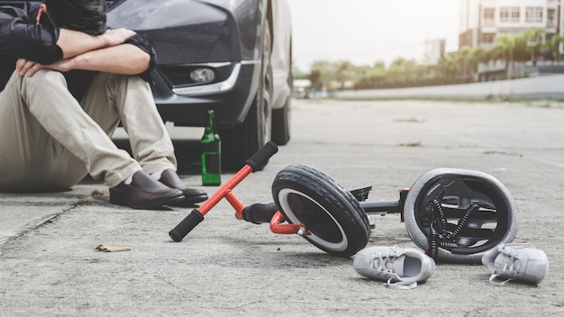 Foto lunghezza completa di un uomo ubriaco seduto da una bicicletta danneggiata sulla strada