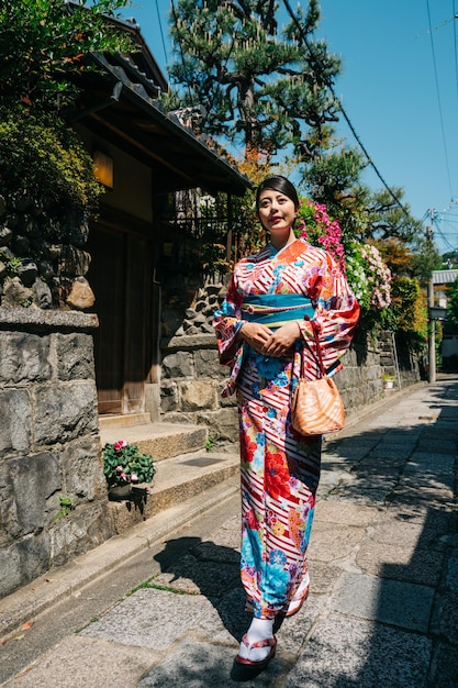 カラフルな着物を着て家を出て、祝福のために寺院に行くエレガントな日本の女性の全長。京都の通りを歩いている若い女の子。アジアの女の子の休日のライフ スタイル。