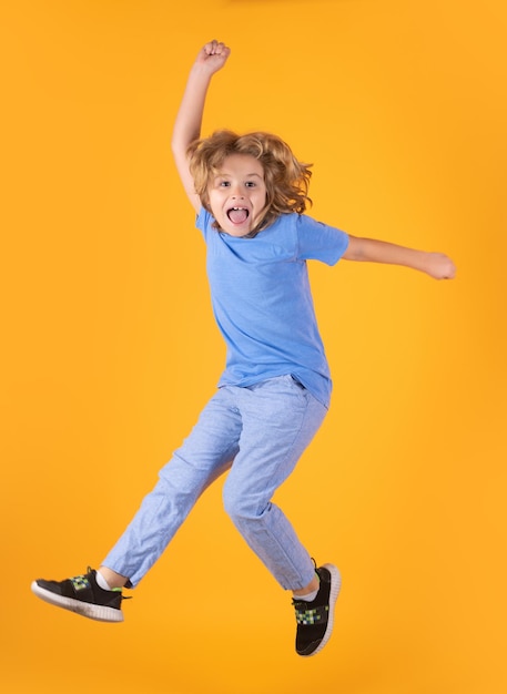 Full length of excited kid jumping Kid boy 89 years old in tshirt jump isolated on yellow background Childhood lifestyle concept Mock up copy space Kid having fun jumping