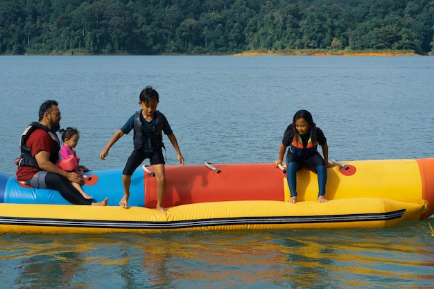 Photo full length of father with kids sitting on boat at lake