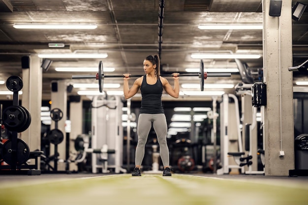 Full length of a female weightlifter lifting barbell in a gym