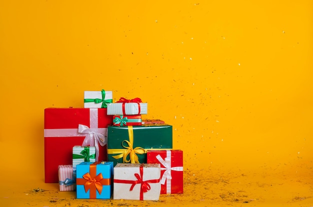 Full-length foto van vele kleurrijke huidige dozen voor Kerstmis, verjaardag of andere vakantie geïsoleerd op gele achtergrond