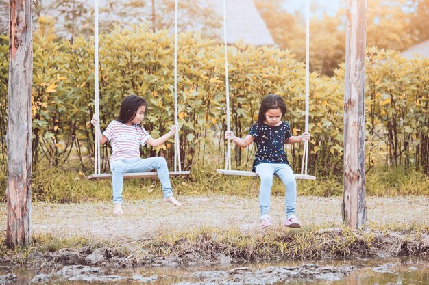 Photo full length of friends playing on swing at field