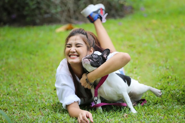 草の上に横たわって犬を抱きしめる女の子の全長