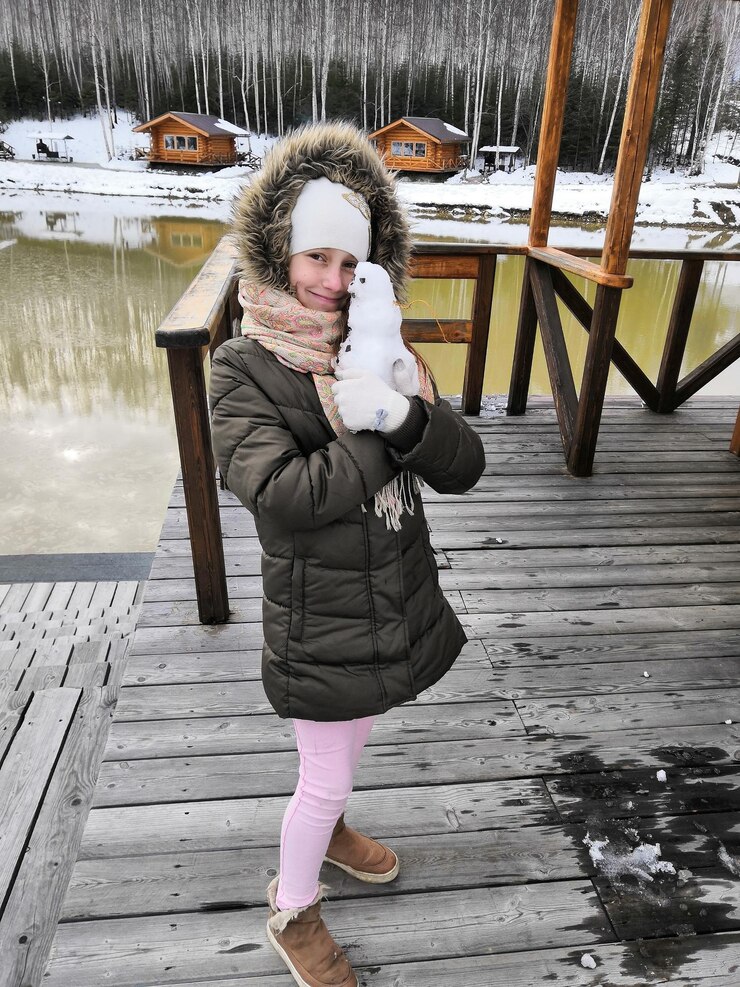 Photo full length of girl holding small snowman while standing on pier
