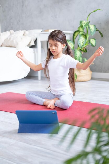 Full length of girl meditating at home