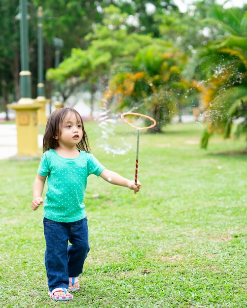 Foto lunghezza completa di una ragazza che gioca con le bolle nel parco