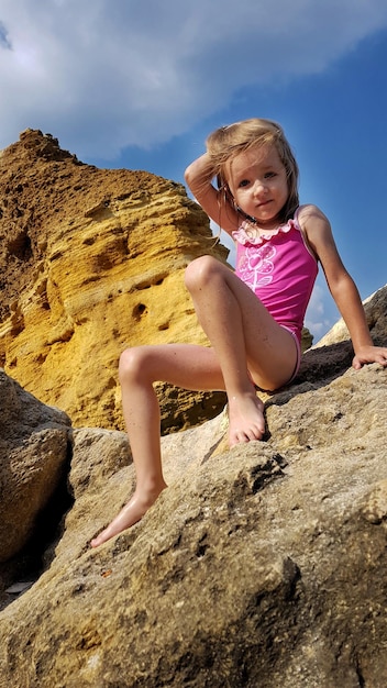 Photo full length of girl on rock against sky