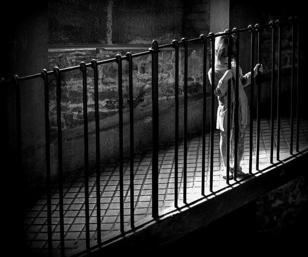 Foto lunghezza completa di una ragazza in piedi sul balcone di notte