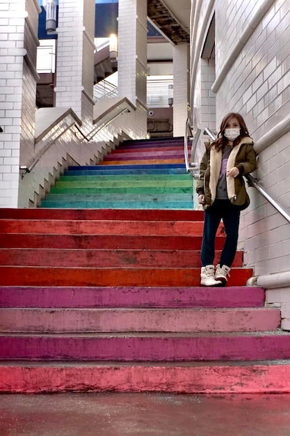 Full length of girl standing on colorful outside staircase