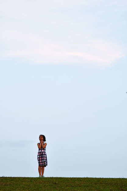 Photo full length of girl standing on field against sky