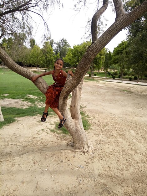 Photo full length of girl on tree trunk