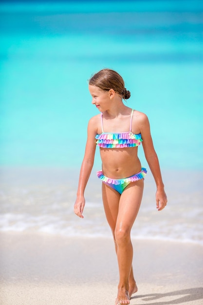 Foto lunghezza completa di una ragazza che indossa un costume da bagno che cammina sulla spiaggia