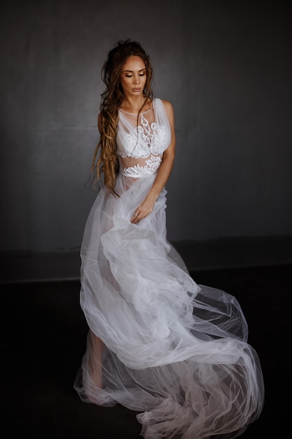 Photo full-length girl in a white tender peignoir. flying transparent fabric