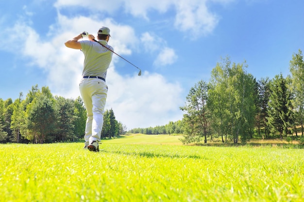 Full length of golf player playing golf on sunny day professional male golfer taking shot on golf course