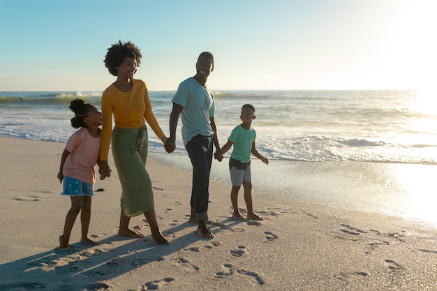 Full length of happy african american family enjoying summer holiday together at beach