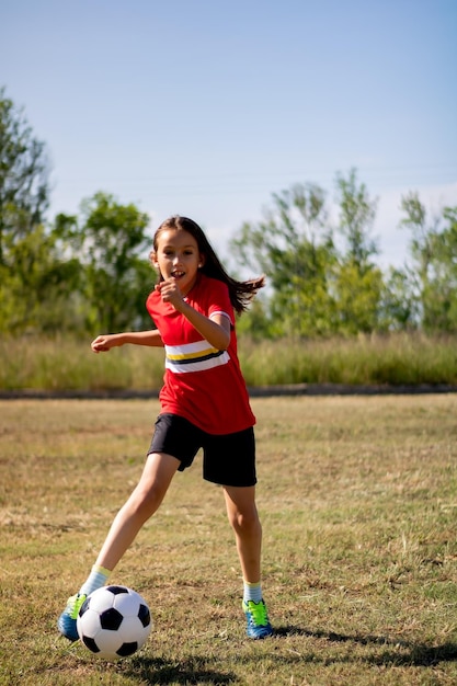 Photo full length of happy boy playing soccer on field