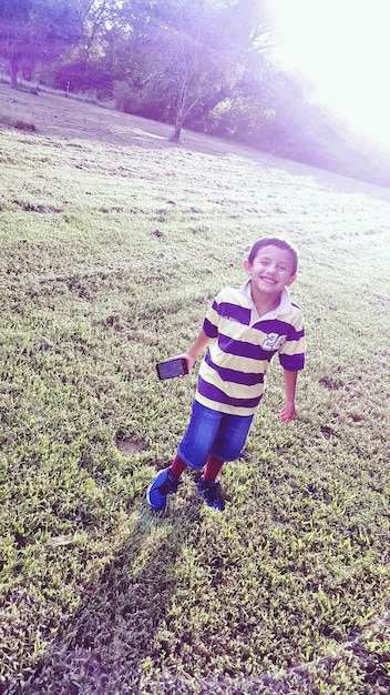 Photo full length of happy boy standing on field