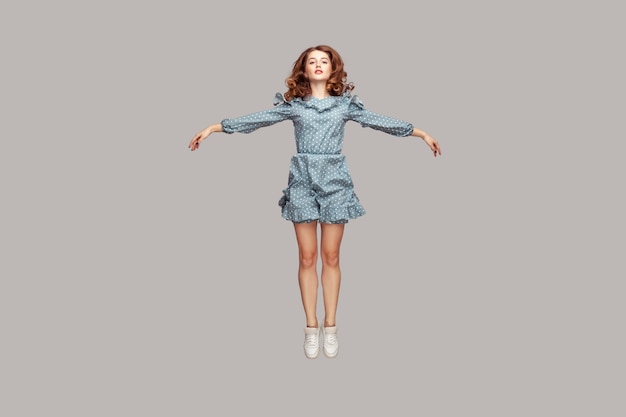 Full length happy calm pretty girl levitating hovering in mid-air with raised hands as wings