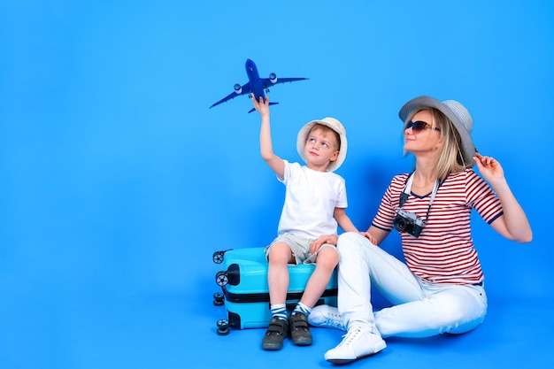 Full length happy excited woman and little boy in summer clothes and hats with toy airplane sitting