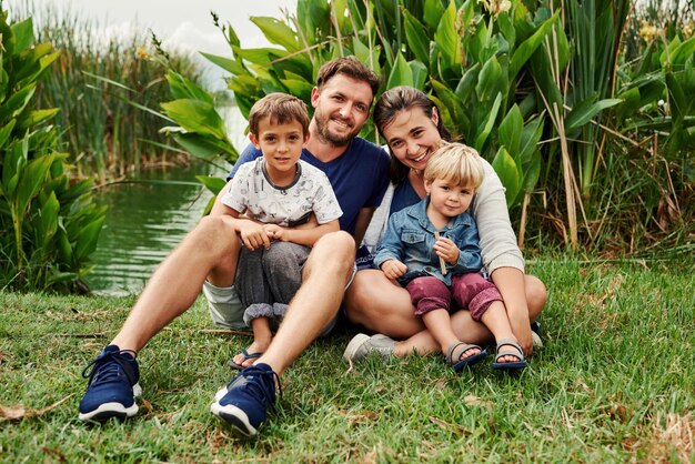 Photo full length of happy family sitting by pond