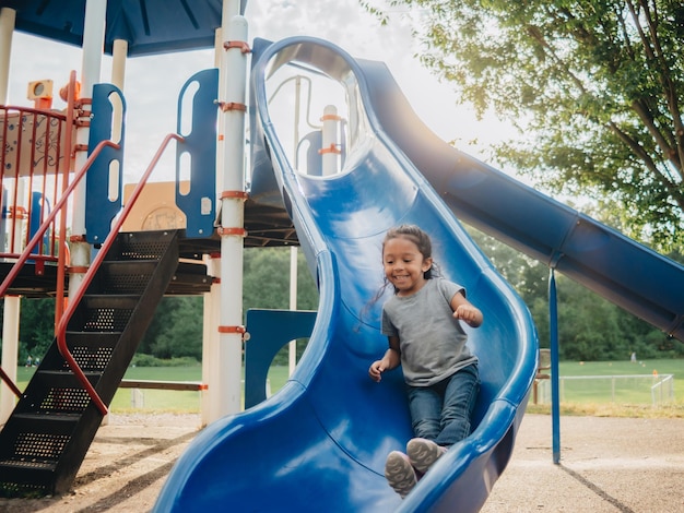 Photo full length of happy girl on slide at playground