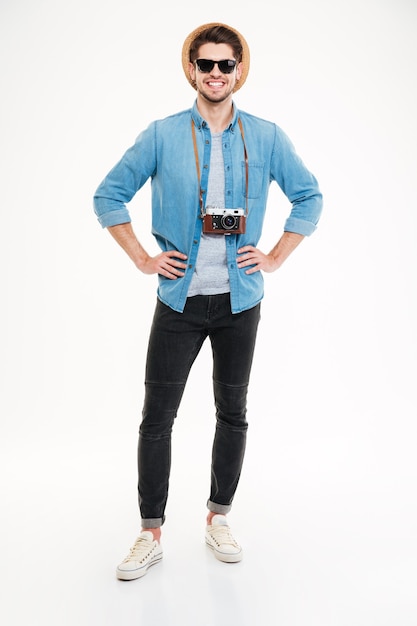 Full length of happy handsome young man with old vintage photo camera over white background