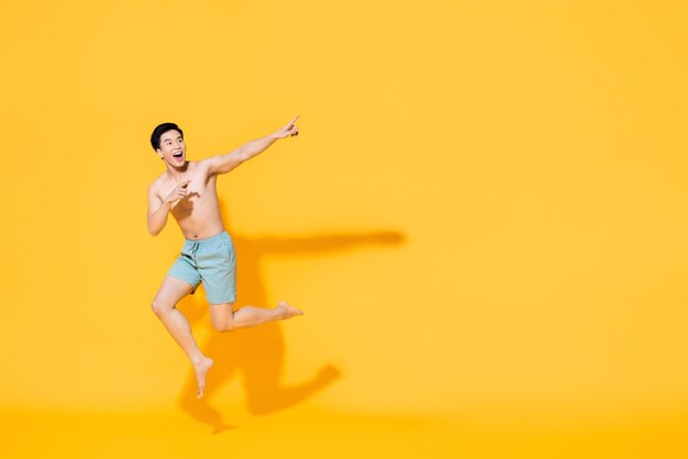 Full length of happy man with arms raised against yellow background