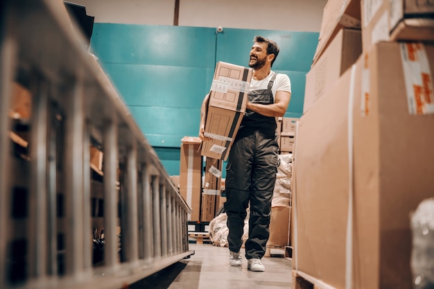 Full length of hardworking worker relocating box in storage