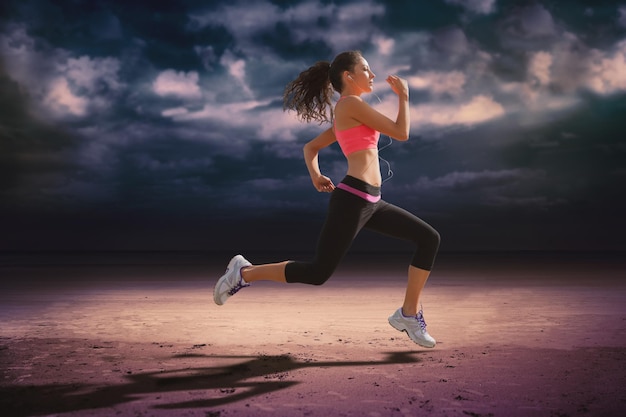 Full length of healthy woman jogging  against dark cloudy sky