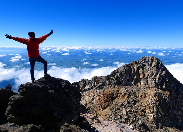 Foto lunghezza completa di un escursionista in piedi su una roccia contro il cielo