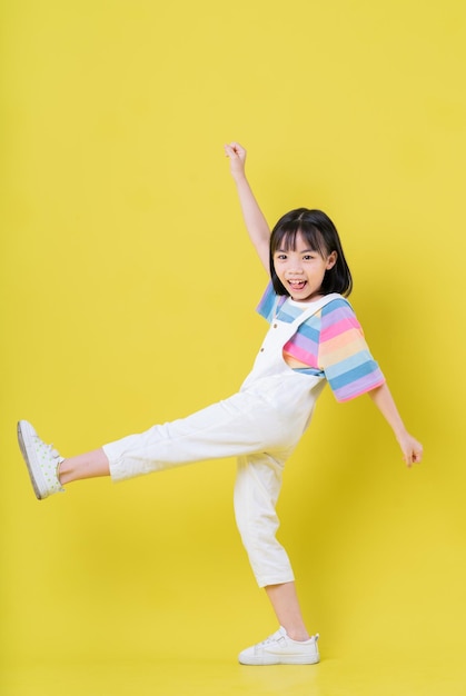 Full length image of Asian child posing on yellow background