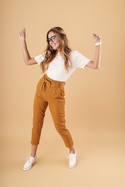 Full length image of happy woman wearing eyeglasses smiling and dancing isolated