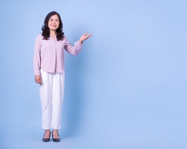 青の背景に中年のアジアの女性の完全な長さの画像