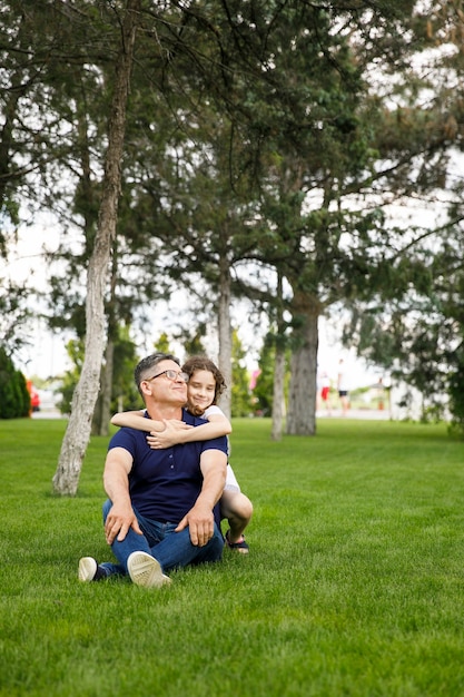 Full length image of a niece hugs her grandfather in the park on a sunny day. Outdoor portrait. Family concept.