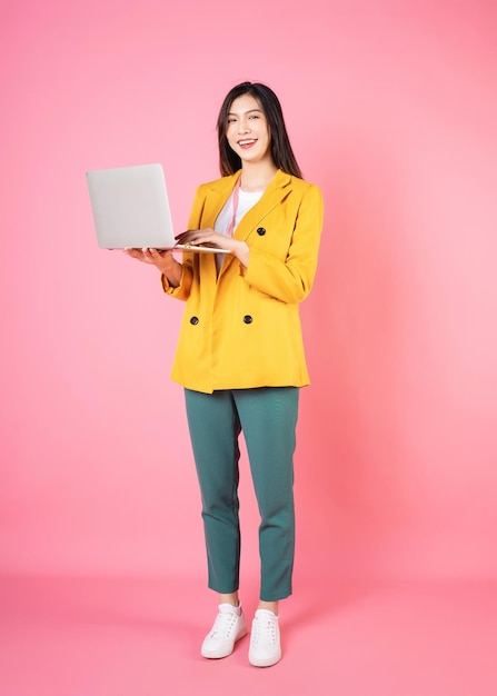 Photo full length image of young asian bussinesswoman holding laptop on background