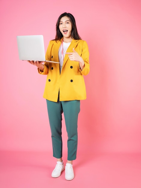 Full length image of young Asian bussinesswoman holding laptop on background