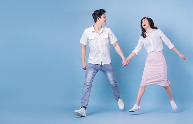 Full length image of young Asian couple on blue background