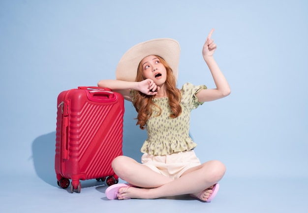 Full length image of young Asian girl with suitcase on blue background travel concept