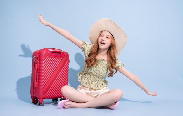 Full length image of young Asian girl with suitcase on blue background travel concept