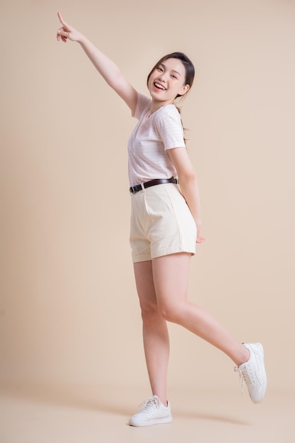 Full length image of young Asian woman posing on background