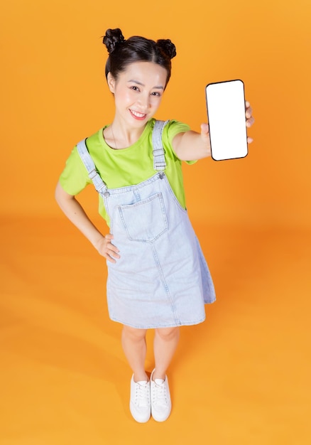 Full length image of young Asian woman standing on background