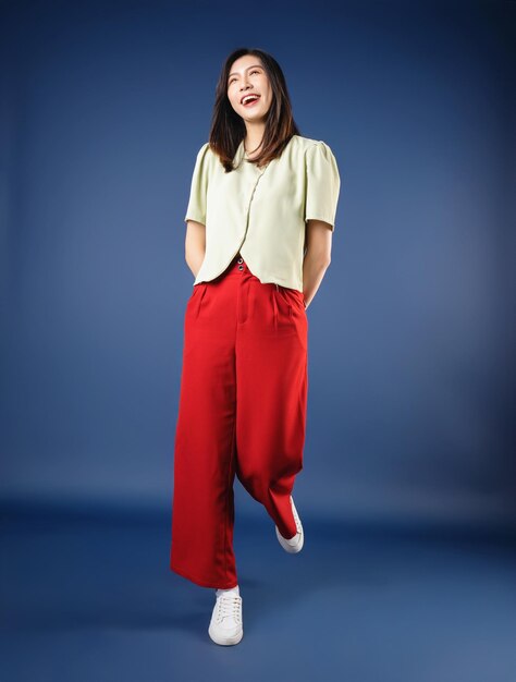 Full length image of young Asian woman standing on background