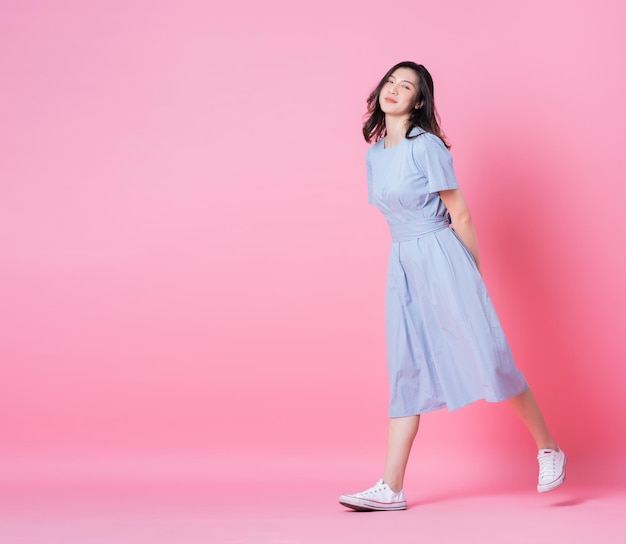 Immagine integrale di giovane donna asiatica che indossa un abito blu su sfondo rosa