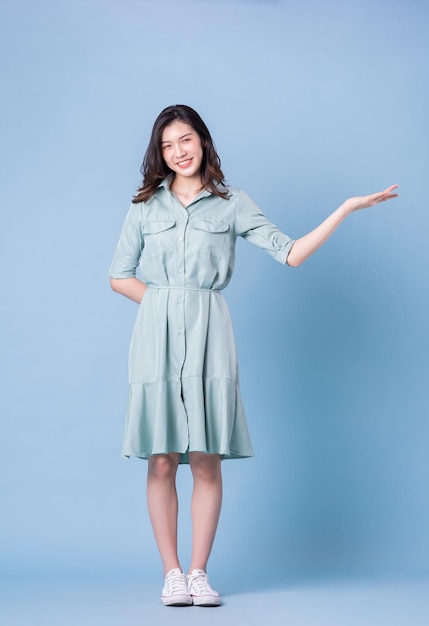 Full length image of young Asian woman wearing dress on blue background