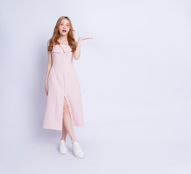 Full length image of young Asian woman wearing dress on white background