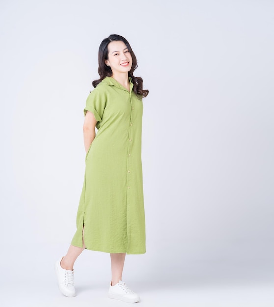 Full length image of young Asian woman wearing green dress on background